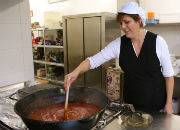 Kok fra Spanien der rører i en stor gryde med tomatsause